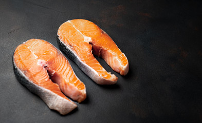 Raw salmon steaks with spices, salt and lemon on the background of old stone