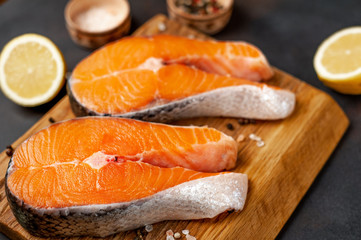 Raw salmon steaks with spices, salt and lemon on the background of old stone