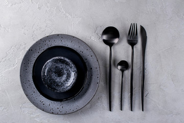 Set of porcelain handcraft  grey and black plates and  bowls cutlery set, linen napkin on a white...
