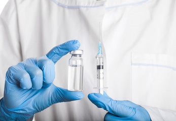 Doctor holding a syringe and a bottle with an injection solution