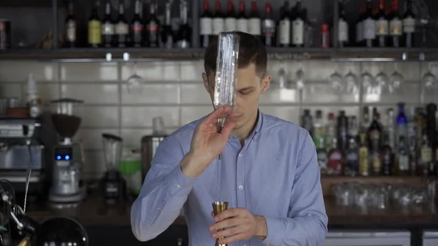 Barman hold bottle and pouring cocktail at the bar