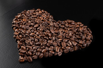 Roasted coffee beans arranged in the shape of a heart on the table. Tasty fragrant coffee in the...