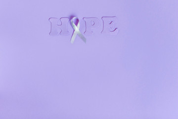 Obraz premium Lilac ribbon with word Hope on lilac background