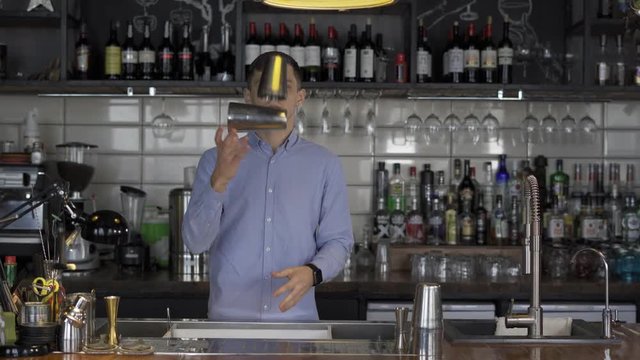 Fantastically beautiful bartender tosses two shakers