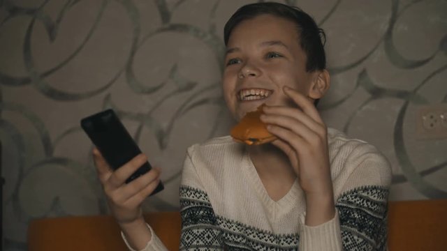 teenager watching television and eating fast food