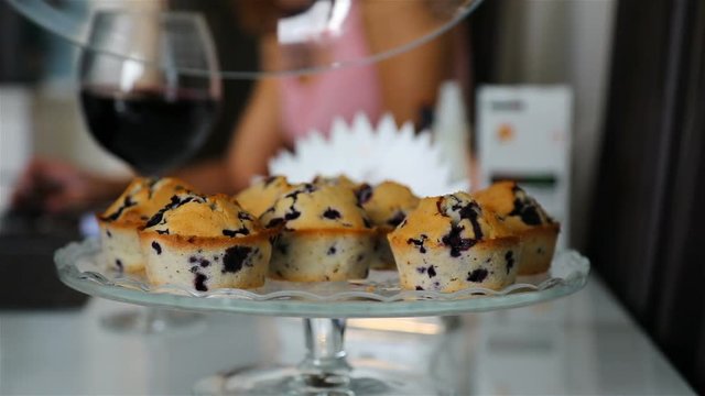 A female hand lifts the lid of a glass tray and takes a cupcake.