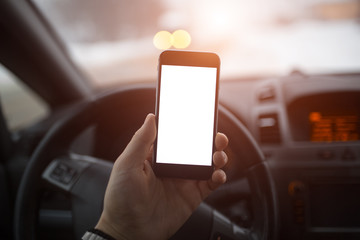Close-up, hand of man holding smartphone with mockup on background of car dashboard.