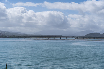 long bridge in New Zealand with blue sky background und the ocean in the foreground