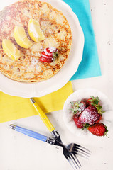 Shrove Pancake Tuesday pancakes with lemons and strawberries with lens flare.