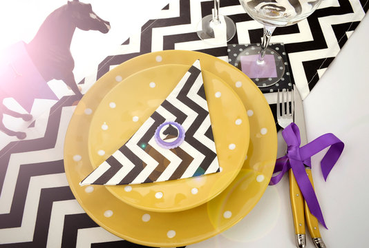 Horse Racing Carnival Event Luncheon Table Place Setting In Purple, Yellow Theme, And Black And White Chevron Strip Table Runner, With Lens Flare.