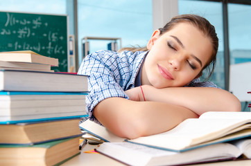 Female student with many books sitting in the classroom