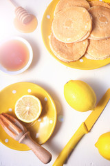 Shrove Tuesday pancakes served with lemon and honey on yellow plates., with retro filters and lens flare.