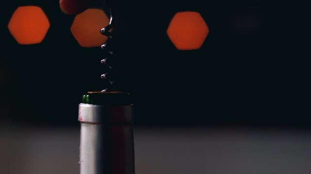 Close-up opening a wine bottle with corkscrew