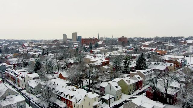 Aerial view of colorful suburbs of Lancaster, Pennsylvania, covered in fresh snow, downtown area with tall ofice buildings in background, winter scene in urban area