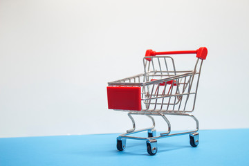 Sale concept. Supermarket trolley on a white wall background.