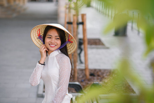 Close up portrait of pretty asian girl dressed in Ao Dai dress wearing vietnamese conical hat.