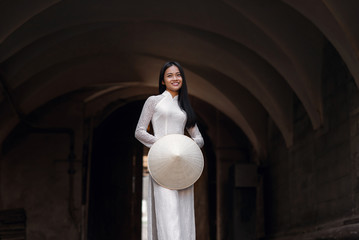 Beautiful happy asian girl dressed in national traditional Ao Dai dress with vietnamese conical hat Non La, Leaf Hat.
