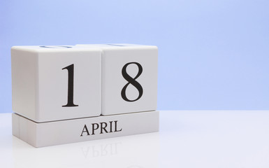 April 18st. Day 18 of month, daily calendar on white table with reflection, with light blue background. Spring time, empty space for text