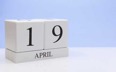 April 19st. Day 19 of month, daily calendar on white table with reflection, with light blue background. Spring time, empty space for text