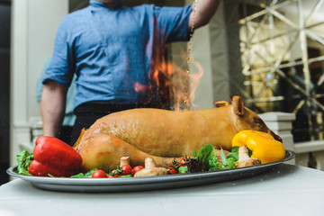roasted pig with vegetables on fire