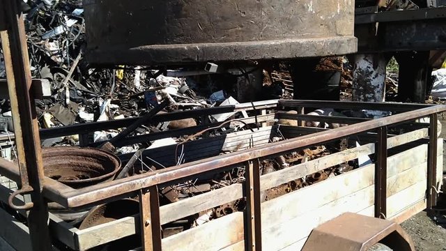 A recycle center grabing metal with a big magnetic machine and putting into a huge pile of metal and garbage, Helping the climate change and the nature
