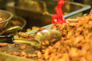 Vendor is selling fried baby squid with garlic in night market at Bangkok, Thailand.