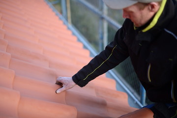 Junger Dachdecker Arbeiter auf dem Bau legt Hand auf das rote Dach zum CHECK. Preis Planung für...