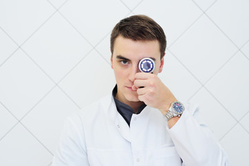 young attractive male doctor dermatologist with Dermatoscope in hand on white background....