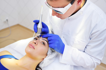the surgeon beautician removes pigmentation and vascular nets on the skin of the patient-a...