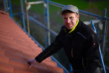 Dachdecker Zimmermann Bau Arbeiter checkt stolz das Dach mit roten Dachziegeln