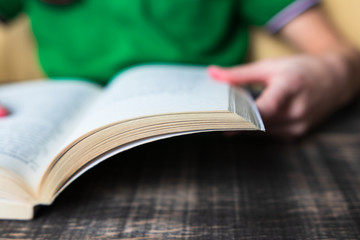defocus. a child in a green T-shirt reads / leafs through a book. Day of knowledge. Hello School. September 1. celebration