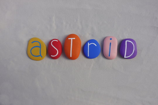 Astrid, feminine given name celebrated with multi colored stones over white sand