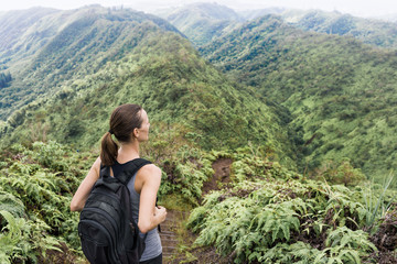 Naklejka na ściany i meble Female hiker hiking through lush green mountains of Oahu (Hawaii)