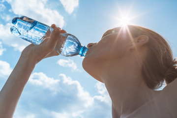 Fototapeta Female drinking bottle of water on a hot summer day. obraz
