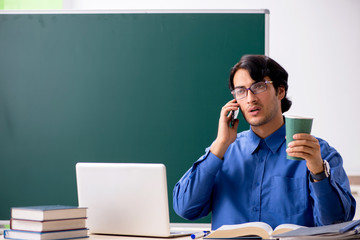 Young male teacher in front of chalkboard