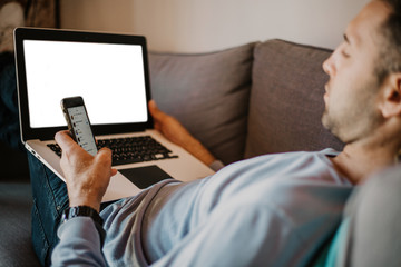 Working moments at home.Young caucasian coworker man in casual clothes working on laptop at sofa at modern apartment. Blurred background.Mock-up.