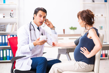 Obraz premium Young doctor checking pregnant woman's blood pressure