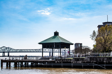 Buildings and a Green Gazebo Line the Waterfront with the Crescent City Connection Bridge in the Background along the Mississippi River in New Orleans, Louisiana, USA