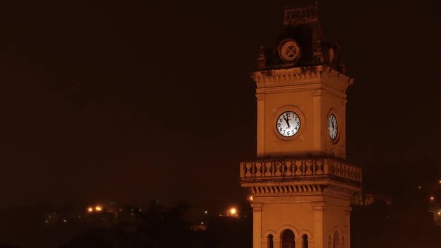 A time lapse of a clocktower, in Brazil, City of Juiz de Fora, during the night time, with a dark sky, and time running fast.