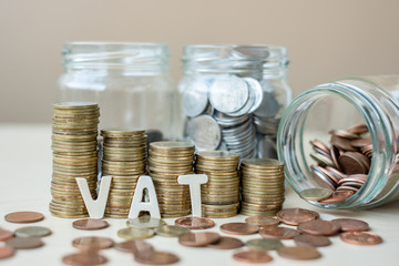 VAT text with golden coin growing money stairs or stack and glass jar on wooden table. business, investment, retirement planning, finance and Saving for the future concepts