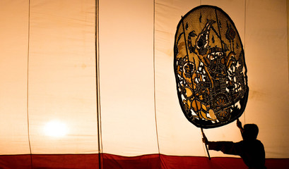 A man is playing an old Thai traditional shadow play called as Nang Yai,Composed to Golden tone.