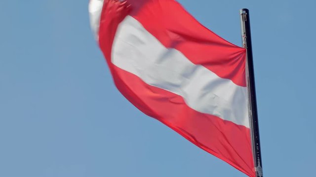 red and white flag of Austria is swaying by wind against clear blue sky