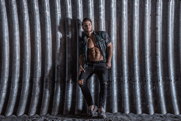 Muscular young man with beard on dark tunnel urban background. Fashion portrait of brutal strong...