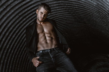 Muscular young man with beard on dark tunnel urban background. Fashion portrait of brutal strong...