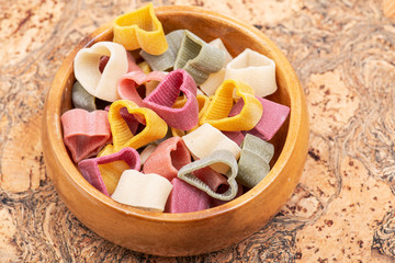 Durum wheat semolina heart-shaped 5 flavors pasta with vegetables in wooden bowl. Valentine's Day. 