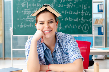 Female student with many books sitting in the classroom