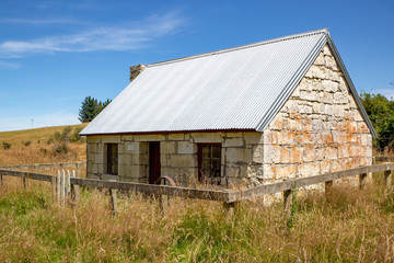 Fototapeta na wymiar Old historic stone cottage for public viewing in a field in New Zealand