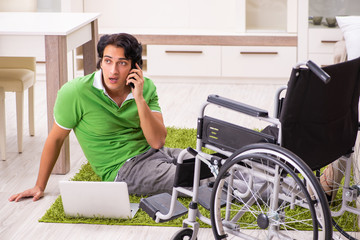 Young handsome man in wheelchair at home