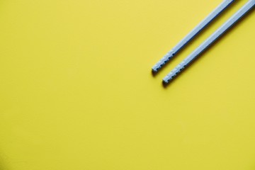 Plastic Blue chopsticks On Yellow Background close up