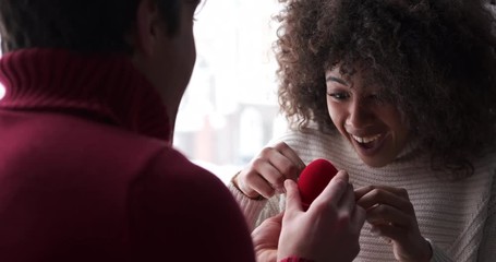 Excited young woman accepting proposal and embracing her boyfriend at home